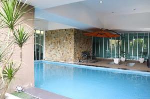 uma piscina com um guarda-sol ao lado de um edifício em The Viana Apartment IV em Kota Bharu