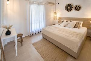 a white bedroom with a bed and a desk and a window at Paris Studios & Apartment in Agia Paraskevi