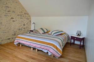 LES CHAMBRES AUX LOUPS في Iffendic: غرفة نوم مع سرير وبطانية ملونة