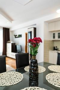 多納瓦利的住宿－ALURE RESIDENCES 4 & 24h self check-in，花瓶,花朵红色,坐在桌子上