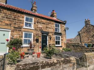 a stone cottage with a white door and windows at Puffin Cottage in Scarborough