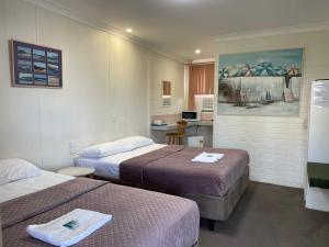 a hotel room with two beds and a kitchen at Bananatown Motel in Coffs Harbour