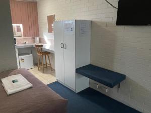 a locker in a room with a chair and a table at Bananatown Motel in Coffs Harbour