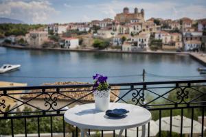 une table avec un vase et des fleurs violettes sur un balcon dans l'établissement Galaxa Mansion, à Galaxidi