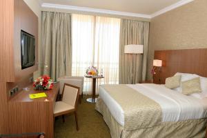 a hotel room with a bed and a desk and a television at Treffen House Doha - next to Msheireb Metro Station and Souq Waqif in Doha