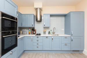 a kitchen with blue cabinets and a sink at Stunning Seaside Apartment Over 3 Floors Near Margate in Westgate-on-Sea
