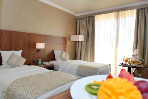 a hotel room with two beds and a table with a plate of food at Treffen House Doha - next to Msheireb Metro Station and Souq Waqif in Doha