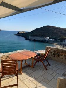 einen Holztisch und Stühle auf einer Terrasse mit Meerblick in der Unterkunft Ikia Wide Wild Summer House in Kollimpithra