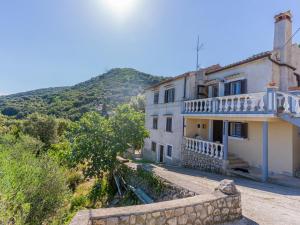 a large white house with a hill in the background at Merag Sunrise Apartment in Cres