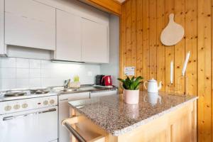 a kitchen with white cabinets and a marble counter top at Center of Veysonnaz with a View ! in Veysonnaz