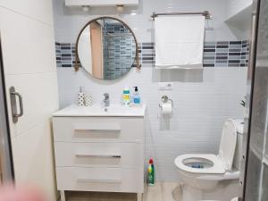 La salle de bains blanche est pourvue de toilettes et d'un miroir. dans l'établissement BRIZO SUITES, à Grao de Castellón