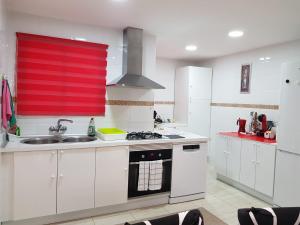 una cocina con armarios blancos y una ventana roja en BRIZO SUITES, en Grao de Castellón