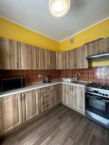 a kitchen with wooden cabinets and a sink and a stove at Apartament Rodzinny in Rumia