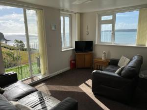a living room with a couch and a tv and windows at Vista Apartments, Goodrington Beach, Paignton in Paignton