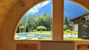 a window in a wooden house looking out at a pool at Aqua Apartments Spa Housemuhlbach in Sappada