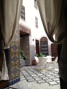 une cour avec une table et des chaises dans un bâtiment dans l'établissement Riad Tizwa Fes, à Fès