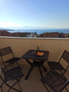 a table with two chairs and a bottle of wine at Villa Rea in Malinska