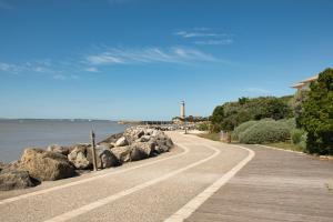 eine Straße am Meer mit Felsen und einem Leuchtturm in der Unterkunft appartement à 300m de la plage in Saint-Georges-de-Didonne