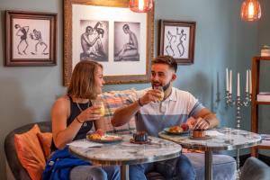 een man en een vrouw aan tafel met drankjes bij Naâd Hotel Sarlat Centre Ville in Sarlat-la-Canéda