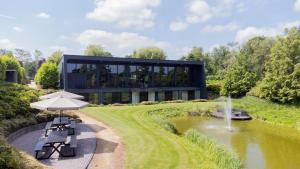 a black building with a pond and a fountain at La Marquise luxe vakantiehuis in Budel