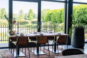 a dining room table with chairs and a large window at La Marquise luxe vakantiehuis in Budel