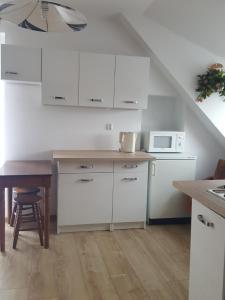 a kitchen with white cabinets and a table and a microwave at Apartament 2pokojowy 4-5osobowy in Węgorzewo +19 photos