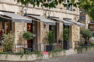 uma frente de loja com guarda-chuvas em frente a um edifício em Naâd Hotel Sarlat Centre Ville em Sarlat-la-Canéda