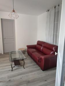 un soggiorno con divano rosso e tavolo in vetro di La maison fleurie 2 a Sainte-Geneviève-lès-Gasny