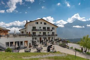 ein großes weißes Gebäude mit Tischen und Stühlen davor in der Unterkunft Berghotel Tgantieni in Lenzerheide