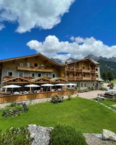 un grand hôtel avec une pelouse devant lui dans l'établissement Landhotel Strasserwirt, à Sankt Ulrich am Pillersee