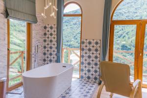 a bathroom with a tub and large windows at Hotel Chateau Iveri in Varjanisi