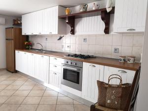una cucina con armadietti bianchi e piano cottura di Appartamento seminterrato Salento ad Alliste