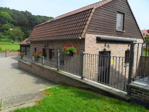 uma casa de tijolos com flores numa cerca em Schophemmerhoeve em Voeren