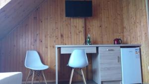 two white chairs sitting next to a counter with a desk at Holiday Ozon in Sztutowo