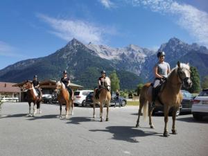 Eine Gruppe von Menschen reitet auf Pferden die Straße hinunter in der Unterkunft Landhotel Strasserwirt in Sankt Ulrich am Pillersee