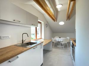 a kitchen with white cabinets and a sink and a table at ANMARI Apartment & Rooms in Radovljica