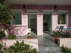 Casa rosa con mesa y sillas en el patio en Livadi Apartments, en Plakias