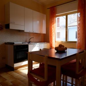 een keuken met een houten tafel met stoelen en een raam bij Ginepro in San Vito