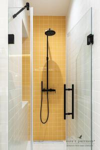 uma casa de banho com um chuveiro e uma parede de azulejos amarelos em White Boat Studio Apartment GOLD em Budapeste