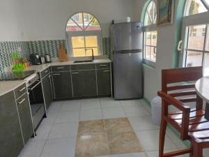 a kitchen with a stainless steel refrigerator and a table at Villa Raven`s Paradise (Gris) in Willemstad
