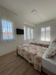 a bedroom with two beds and two windows at Adil Pansiyon in Çeşme