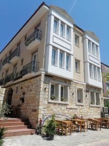 un bâtiment avec des tables et des chaises devant lui dans l'établissement Adil Pansiyon, à Çeşme