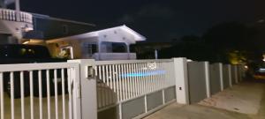 a white fence in front of a house at night at Villa Raven`s Paradise (Gris) in Willemstad