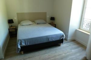 een slaapkamer met een bed met 2 nachtkastjes en 2 ramen bij Chez Berni in Millau
