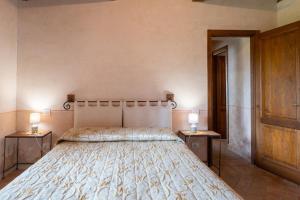 ピティリアーノにあるAgriturismo Tenuta Roccacciaのベッドルーム1室(ベッド1台、ランプ2つ、テーブル2台付)