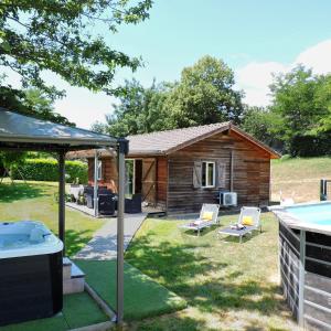 a log cabin with a hot tub in a yard at Chalet Mélèze - Les Chalets de Barruérot - Spa jacuzzi privatif - Piscine en été in Peyrusse-Grande