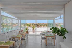 a dining room with tables and chairs and windows at Hotel Vega in Lampedusa