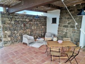un patio con una pared de piedra y una mesa y sillas de madera. en Dammuso Surya Oleandro en Pantelleria