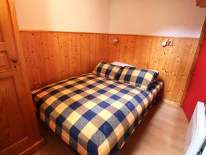 a small bed in a room with wooden walls at Charmant T2 cabine 4 pers, centre-village, proche pistes et commerces, balcon sud, piscine l'été - FR-1-342-145 in Arêches