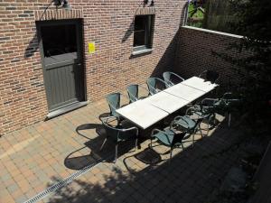 - une table de pique-nique et des chaises devant un bâtiment en briques dans l'établissement Schophemmerhoeve, à Fourons